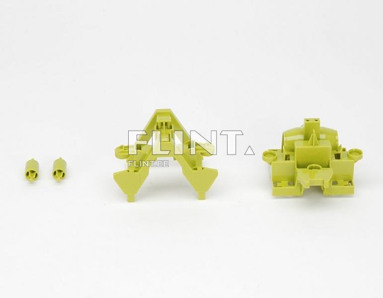 The image displays two plastic components in a light green color set against a white background. On the left, there is a component shaped like an 'A' with two curved legs. On the right, there is a component featuring a flat, wider base with several upward-facing features.