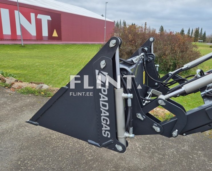 Pildil on nähtav ekskavaatori tööriist, millel on must terasest labidas ja selgelt nähtav PADAGAS logo. Tööriist on paigutatud maapinnale ja taustal on roheline muru.